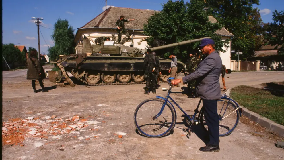 Un hombre en bicicleta ante la dotación de un carro de combate