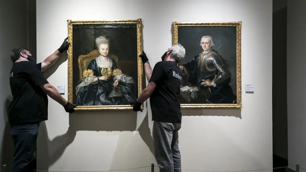 Dos operarios cuelgan el segundo de los retratos en su emplazamiento actual, en la Sala Goya del museo.
