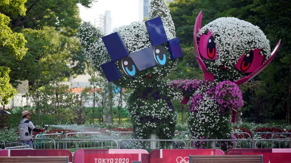 Un jardinero riega las reproducciones de las mascotas de los Juegos de Tokio