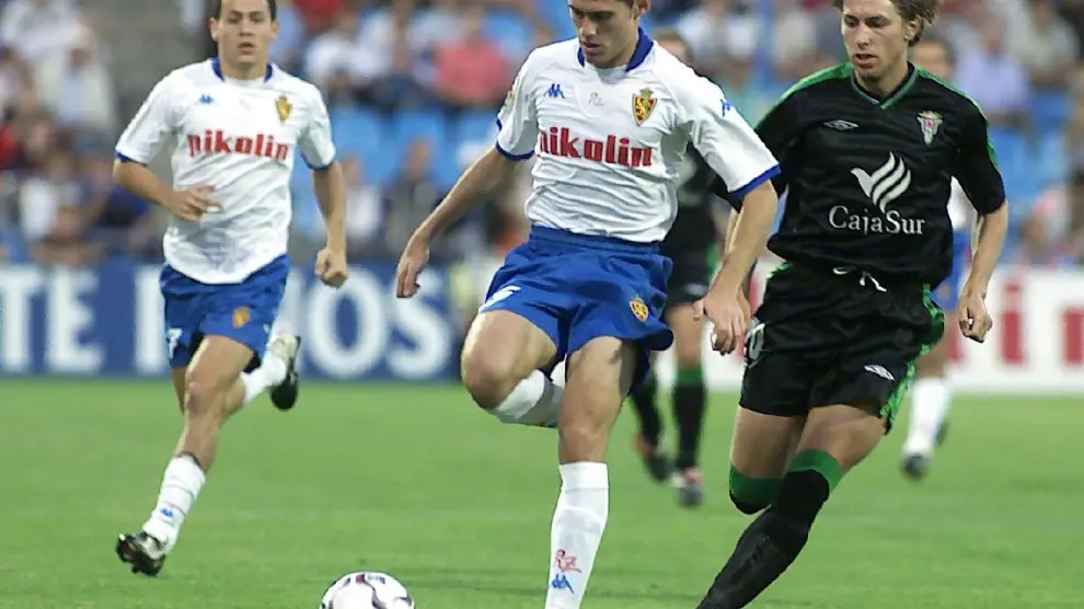Corona conduce la pelota ante un rival cordobés, con Galletti siguiendo la jugada por detrás, en el partido Real Zaragoza-Córdoba del inicio de la liga 2002-03 que acabó 0-0 en La Romareda.