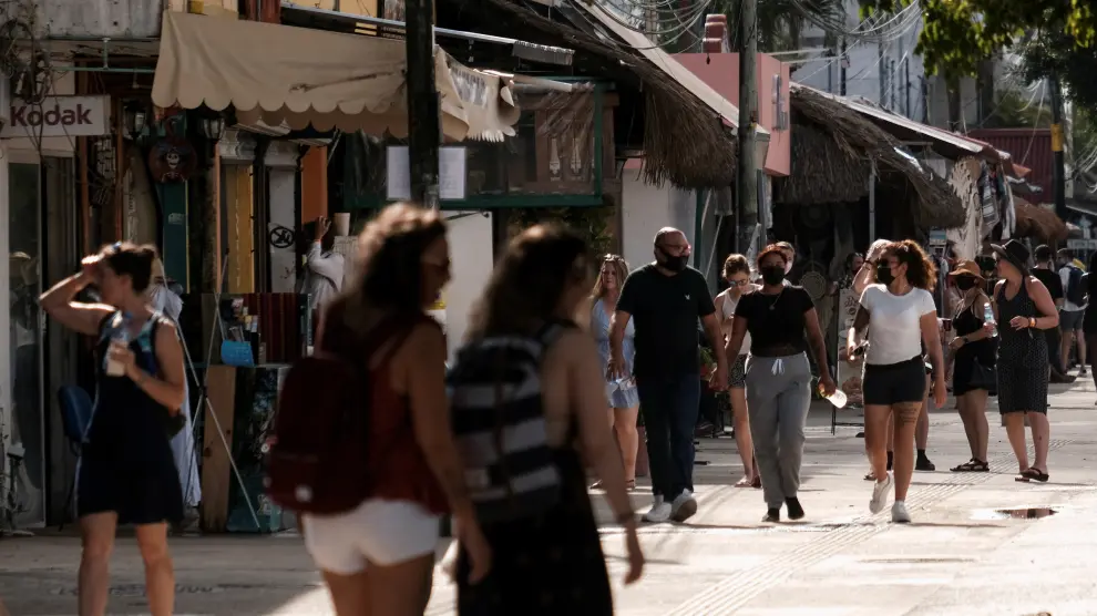 People walk along a street near a restaurant where, according to local media, two foreigners were killed and three injured during a shooting occurred between suspected gang members, in Tulum