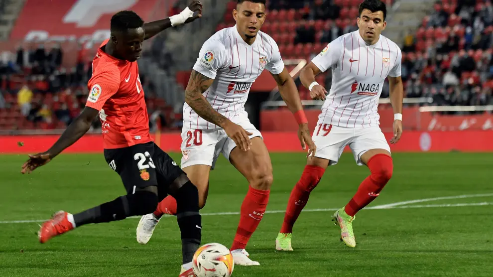 El delantero senegalés del Mallorca, Amath Ndiaye, disputa un balón con Diego Carlos y Marcos Acuña, defensas del Sevilla.