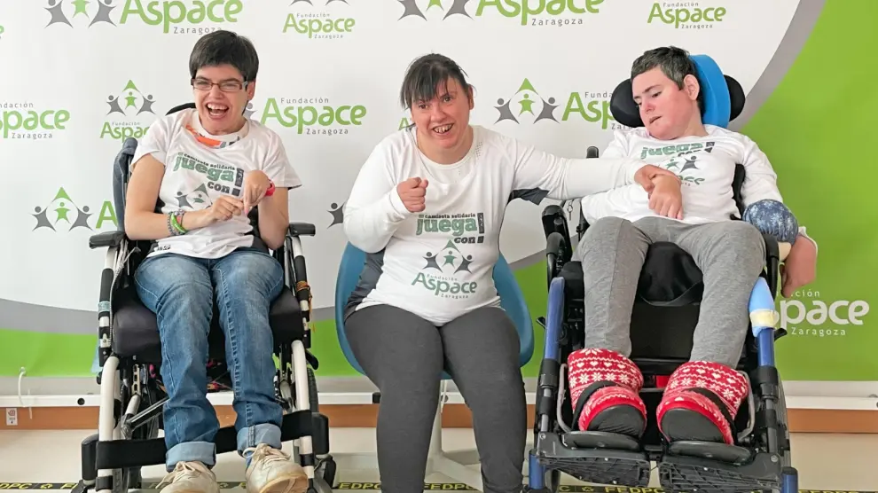 Personas de Aspace exhiben en la camiseta el lema 'juega con Aspace' para animar a la gente a que participe en el pádel solidario.