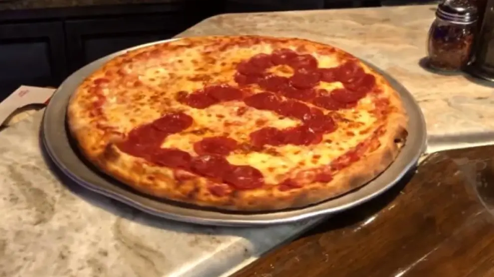 Una pizza con el insulto a Biden escrito con tomate.