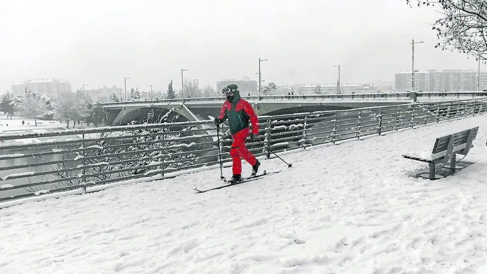 Contra los desmanes de Filomena, imaginación: un joven improvisa una pista de nieve a orillas del Ebro y el puente de Santiago.