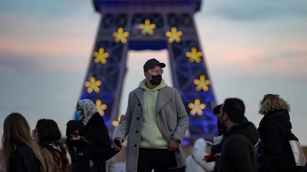 Varias personas delante de la Torre Eiffel de París, que tiene estos días una iluminación dedicada a la Unión Europea FRANCE COVID19 PANDEMIC