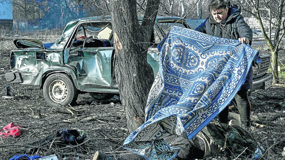 Un vecino de Chugiv, en el este de Ucrania, tapa con una manta a una víctima de los ataques rusos