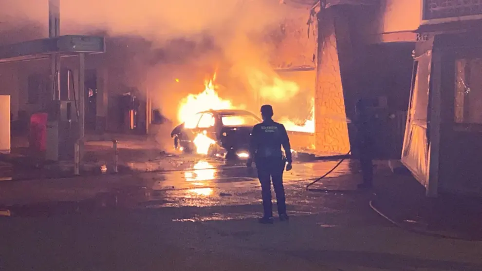La Guardia Civil intenta apagar el coche incendiado en la gasolinera
