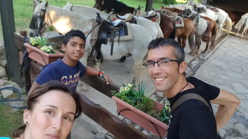 El joven saharaui Gailani, de 13 años, con la pareja aragonesa formada por Ricardo Pérez y Silvia Grustán, el verano de 2019 en Sarvisé (Huesca) visitando a unos caballos.