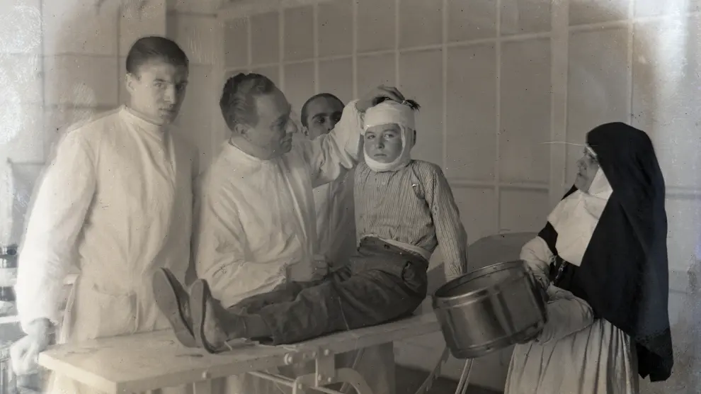 Varias médicos y una monja enfermera junto a un niño posiblemente aquejado de paperas.