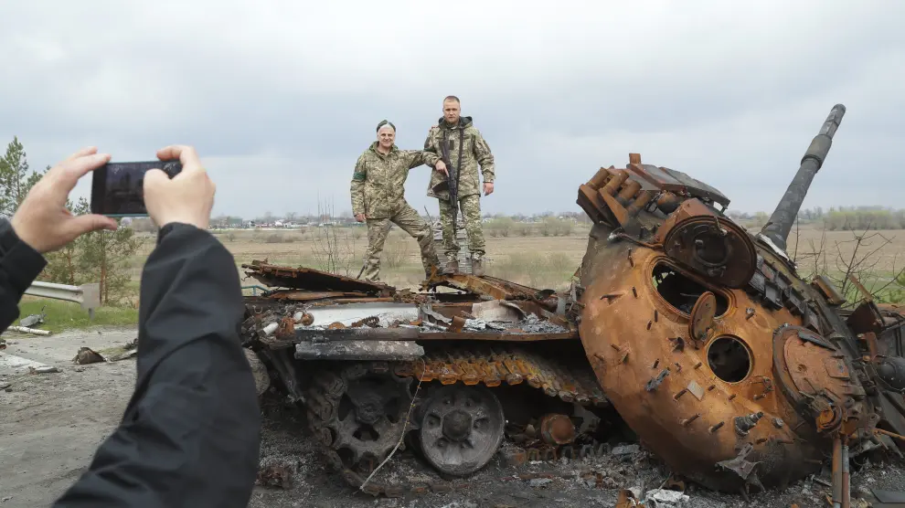 Dos soldados ucranianos posan para una foto sobre un tanque ruso destruido cerca de Kiev
