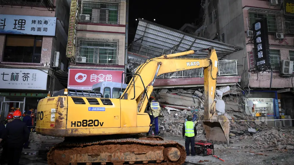 Rescuers work next to an excavator at a site where a building collapsed in Changsha, Hunan