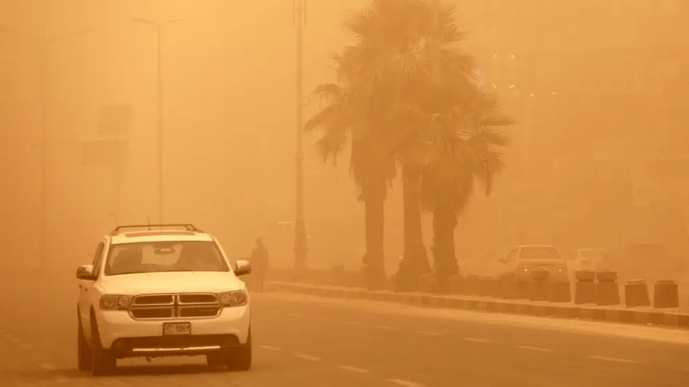 Un coche circula por una calle de Bagdad en medio de la tormenta de arena. IRAQ WEATHER022.- A car driv