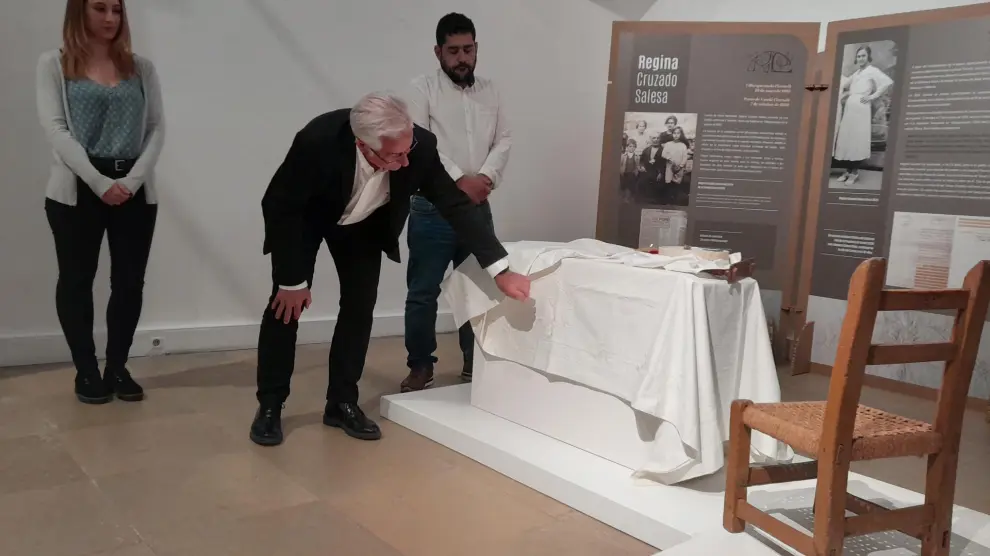 El director del Museo de Teruel, Jaime Vicente Redón -junto al diputado Diego Piñeiro y la experta en exposiciones Sara Civera- muestra los detallas del ajuar que bordó Regina Cruzado.