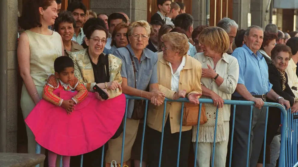 Un grupo de personas, entre ellas un niño vestido de torero, espera al entonces príncipe Felipe en una calle de Jaca.