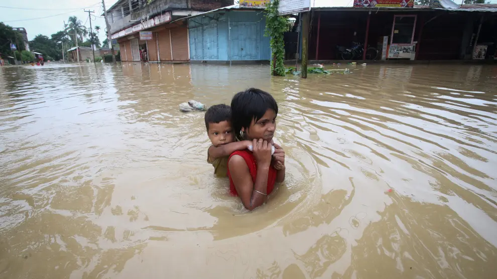 Una niña carga con su hermano en las inundaciones de Agartala, en la India.