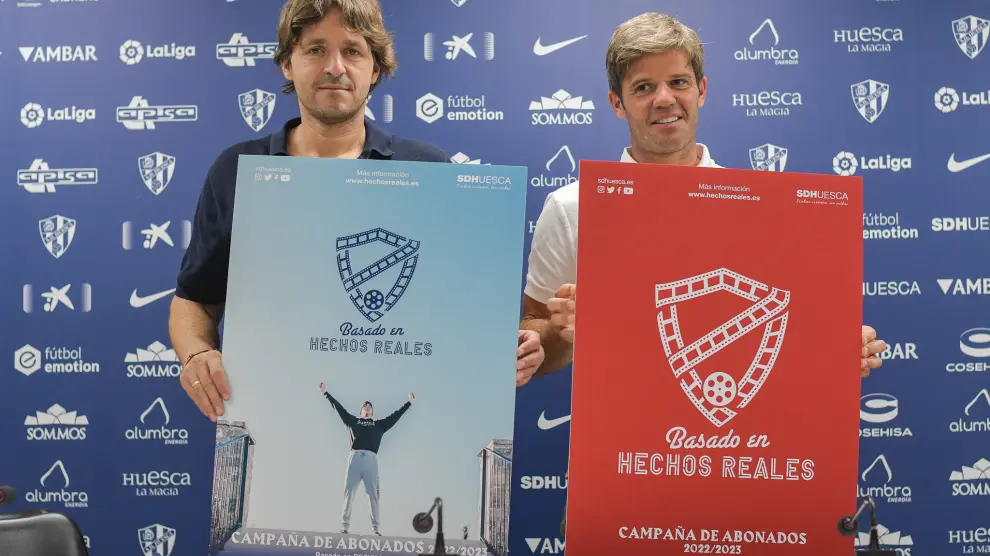 Josete Ortas y Agustín Pueyo sostienen los carteles de la campaña de abonados de la SD Huesca para la temporada 2022-23.