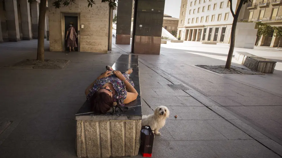 Una mujer descansa sobre un banco de la plaza del Pilar este jueves por la tarde