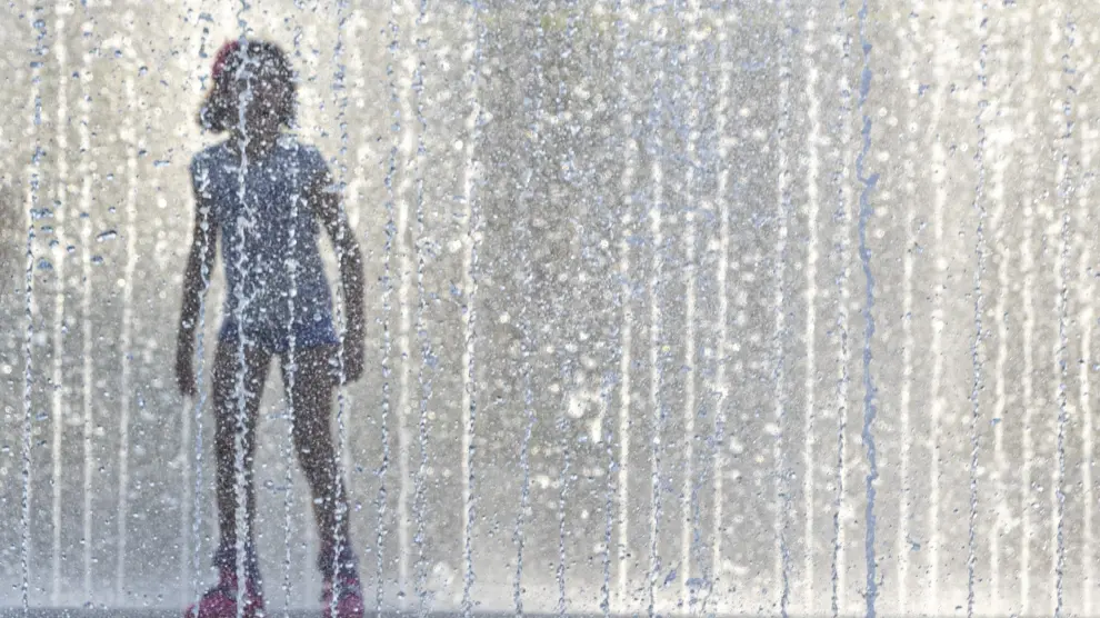 Una niña se refresca en una fuente de Zaragoza durante una de las tres olas de calor de este verano.