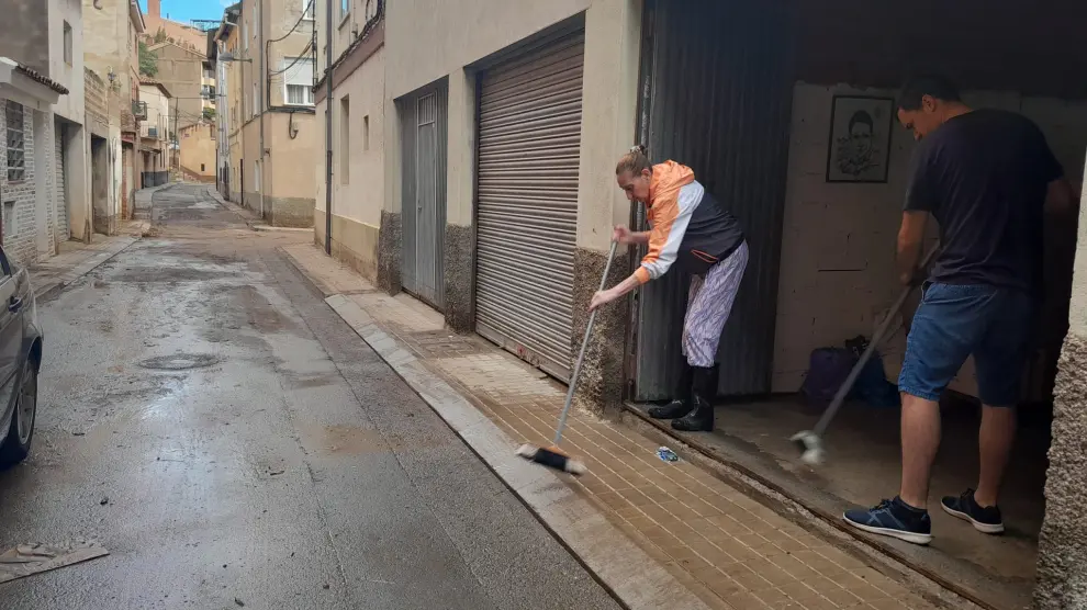 Dos vecinos del barrio de San Julián limpian de barro su garaje.