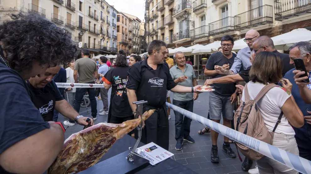 Un grupo de aficionados al corte despacha un jamón en la plaza del Torico e invita al público.