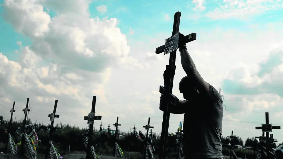 Un voluntario coloca el pasado agosto un cruz con un número en una tumba anónima entre enterramientos de asesinados por tropas rusas en Bucha