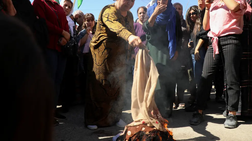 Women burn headscarves during a protest over the death of Mahsa Amini in Iran, in the Kurdish-controlled city of Qamishli