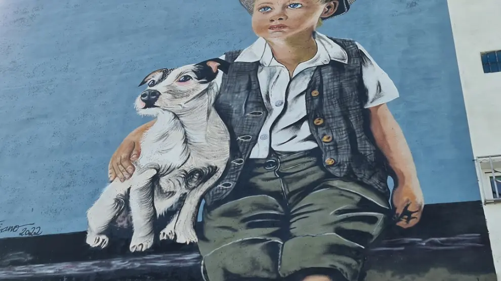 Txus Montejano ha pintado un niño con un perro en un edificio que se halla en la salida de Binéfar hacia San Esteban de Litera.
