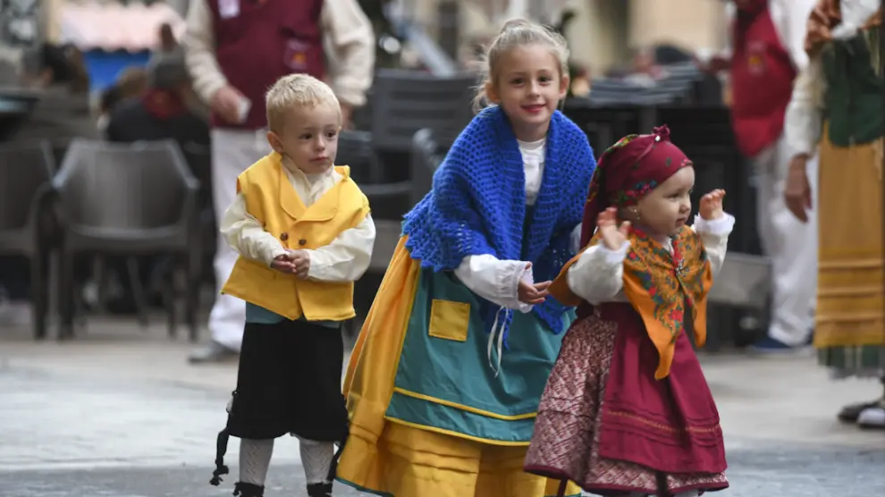 Unos niños, con trajes en tonalidades amarillas, azules, verdes y rojas.