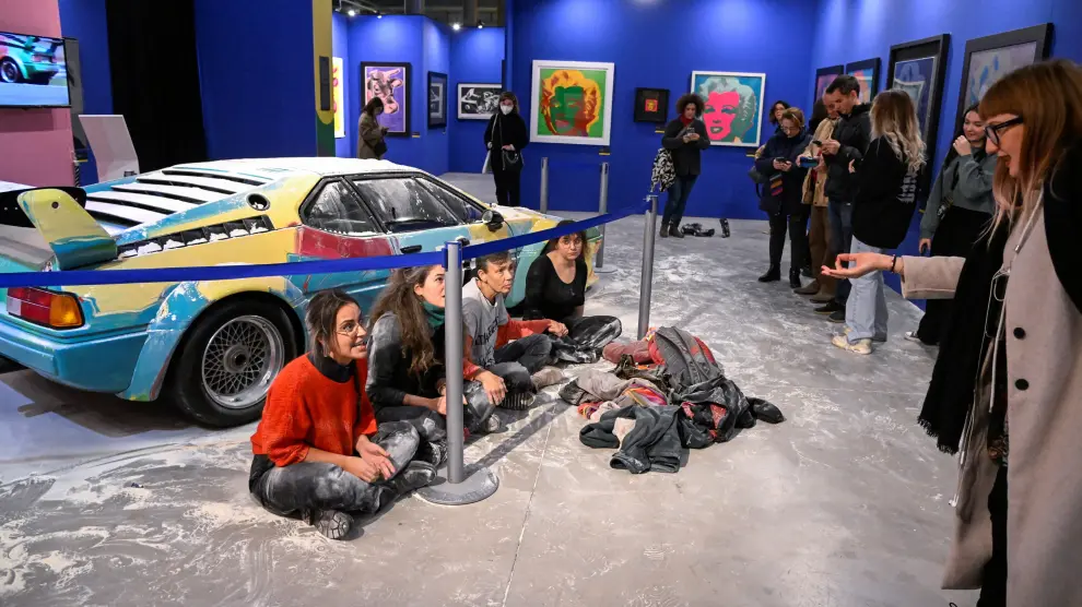 Los activistas, delante del coche diseñado por Andy Warhol que se expone en Milán y ha sido rociado con harina.