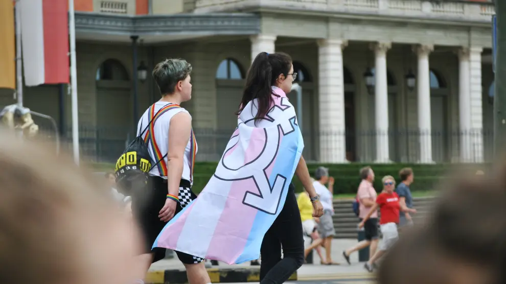 Personas portan la bandera trans con el símbolo del género neutro