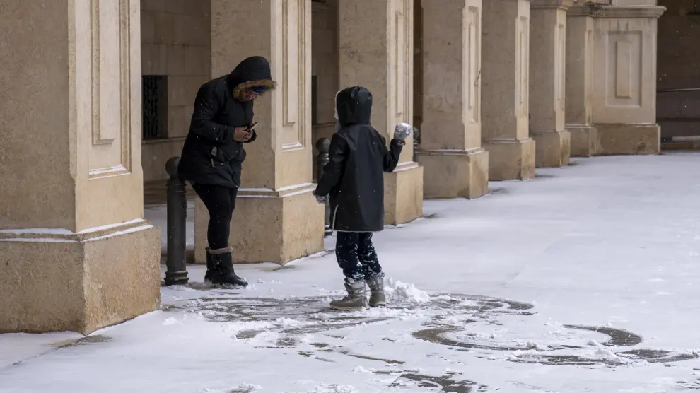 Un niño aprovecha la fina capa de nieve para jugar en la plaza de San Juan.