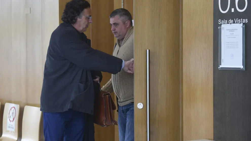El guardia civil condenado por abusos, con chaqueta marrón, saliendo de la sala de vistas de la Audiencia de Huesca con su abogado.