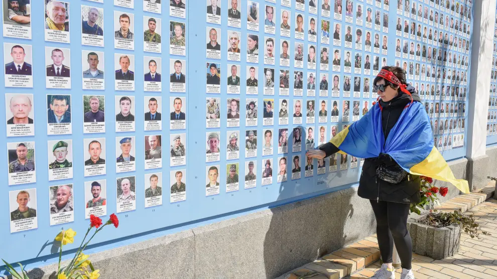 Una mujer mira las imágenes de los soldados ucranianos caídos en combate