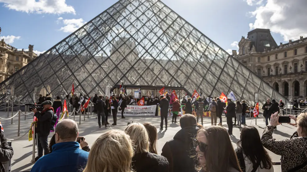 Visitantes esperan fuera del Museo del Louvre mientras los empleados bloquean la entrada.