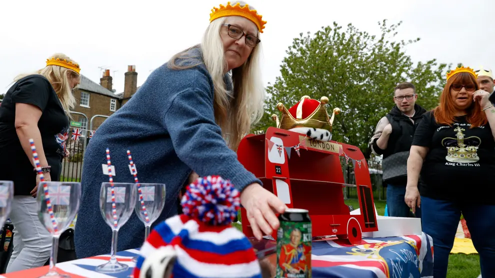 A woman places a beer can with the picture of Britain's King Charles on it, as she sets up a table during a picnic at Windsor Castle, in Windsor, Britain May 7, 2023. REUTERS/Stephanie Lecocq BRITAIN-ROYALS/CORONATION