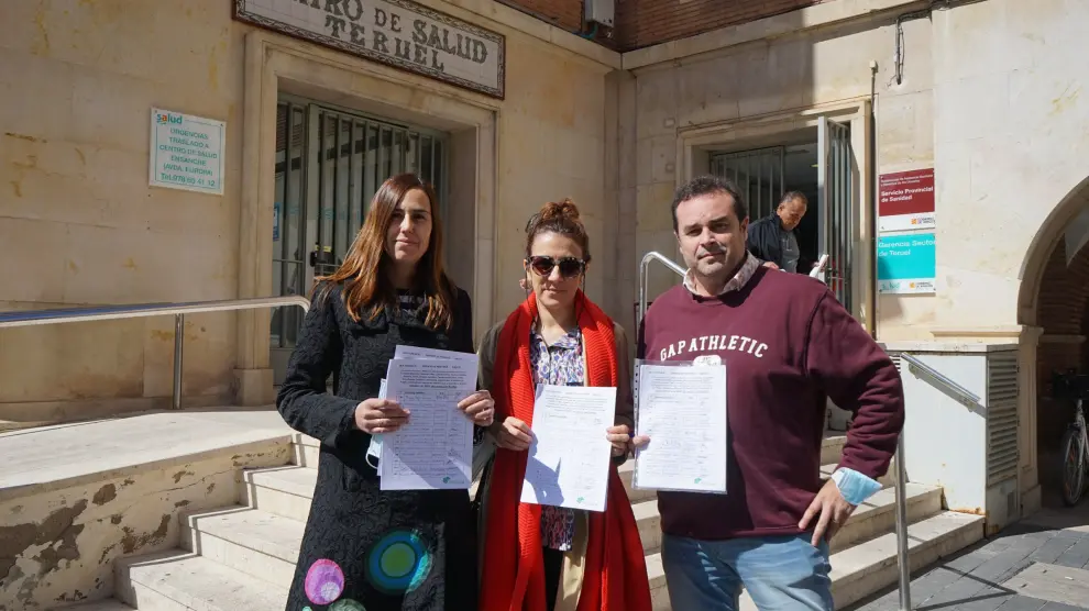 Representantes de Teruel Existe y de las familias muestran las firmas ante el edificio del Servicio Aragonés de Salud.