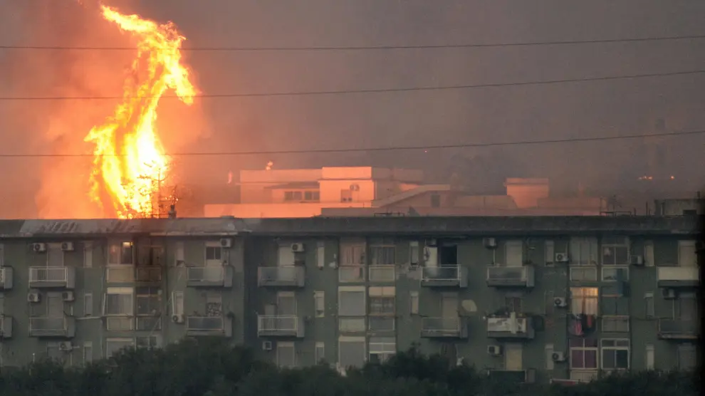 Una columna de fuego se eleva tras un bloque de viviendas en la ciudad de Ciaculli, cerca de Palermo.