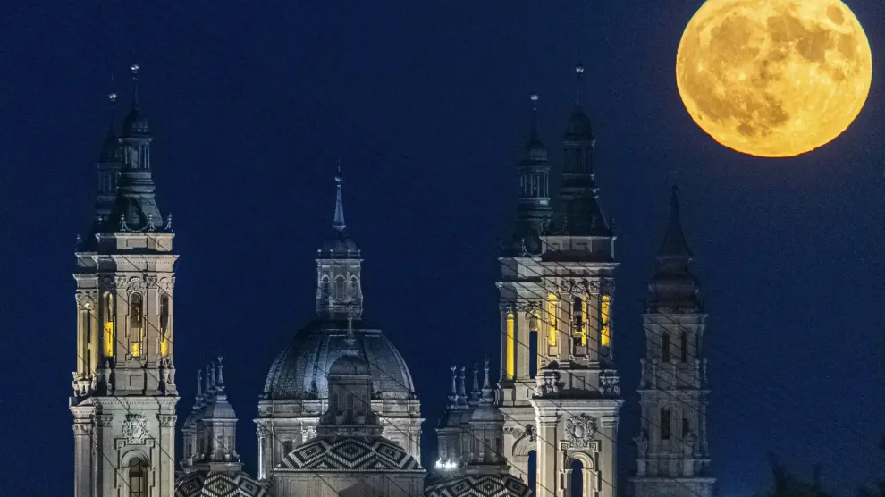 Vista de la primera superluna de agosto emergiendo sobre la Basílica del Pilar, en Zaragoza.