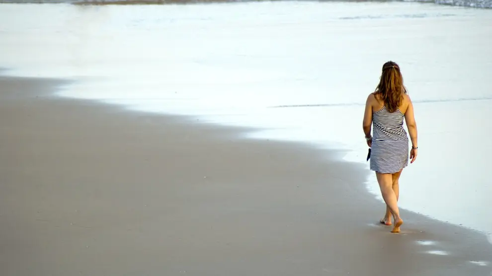 Una mujer camina por la playa.