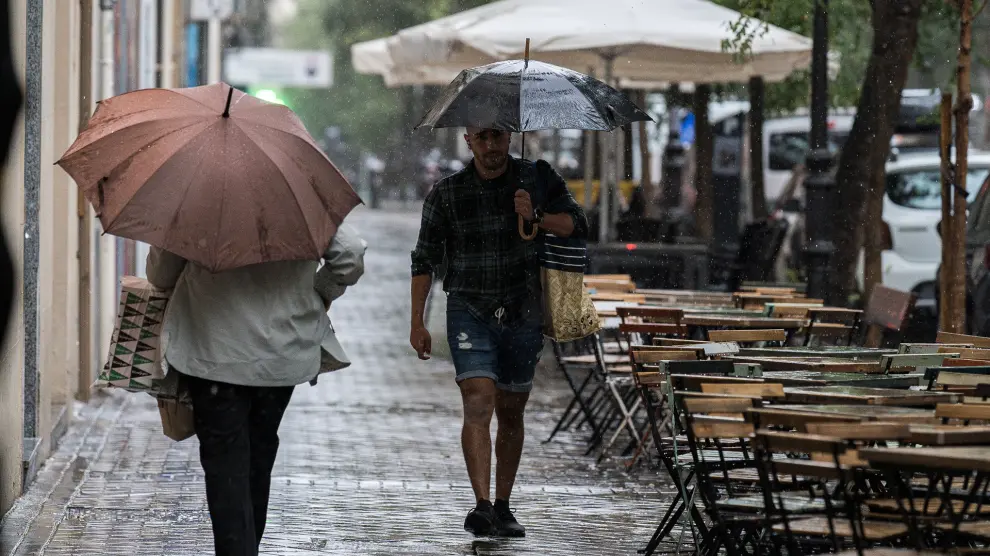Varias personas se resguardan de la lluvia con paraguas, en Madrid (España).