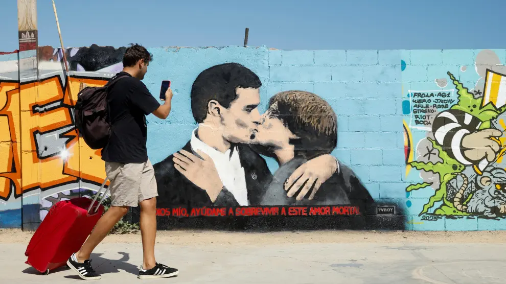 Un hombre hace una foto en Barcelona a un grafiti en el que aparecen Sánchez y Puigdemont besándose