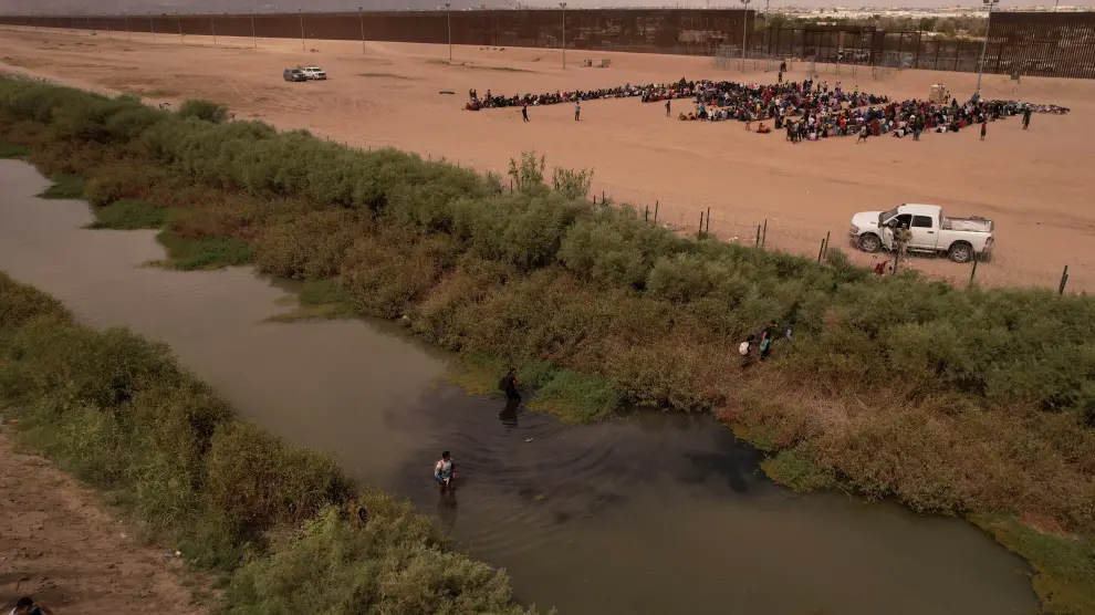 Inmigrantes cerca del muro fronterizo después de cruzar el río Bravo