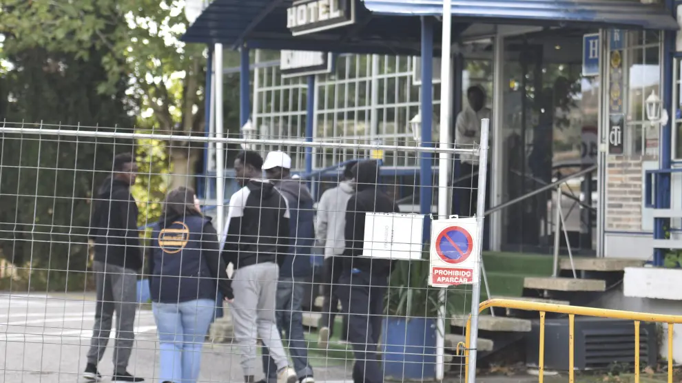 Migrantes atendidos por una trabajadora de la ong Apip-Acam a las puertas del Hotel Montearagón de Huesca.