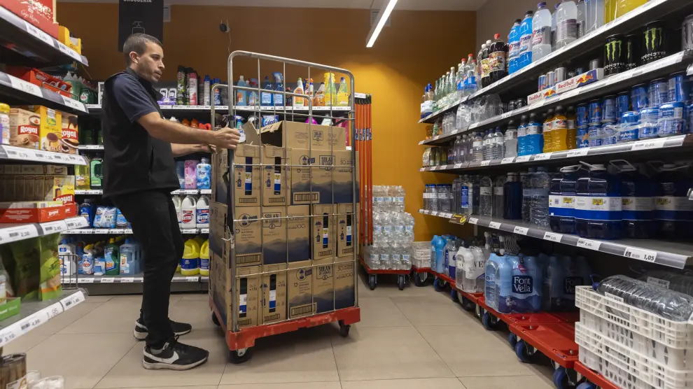 Un trabajador repone agua en las estanterías de un supermercado de Tarazona