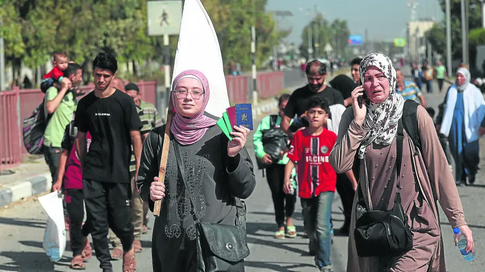 Una mujer palestina sostiene una bandera blanca mientras un grupo de civiles es evacuado desde el norte de la Franja de Gaza hacia el sur