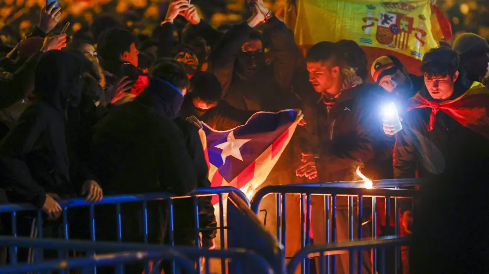 Manifestantes queman una estelada durante la protesta convocada contra la amnistía y el Gobierno de Pedro Sánchez, investido como presidente hoy jueves, en las inmediaciones de la sede del PSOE, en la madrileña calle de Ferraz.