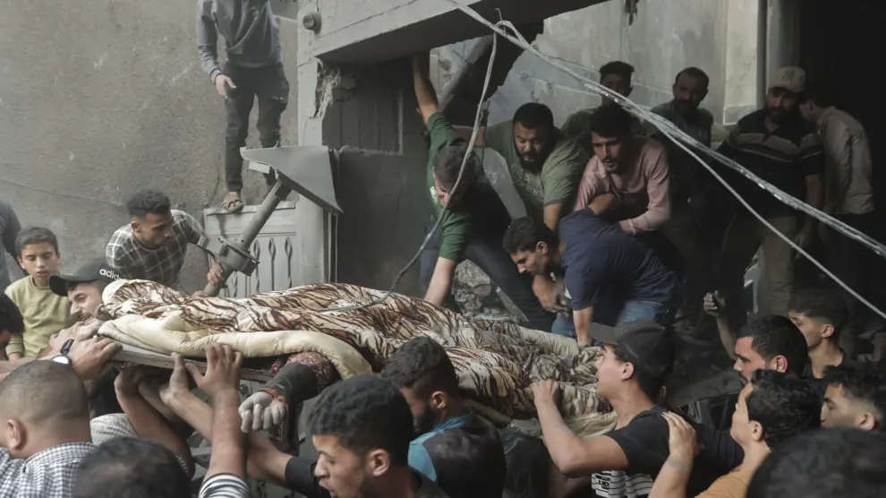 Varios palestinos rescatan un cadáver entre los escombros de un edificio