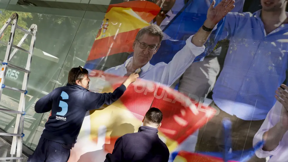 MADRID, 22/11/2023.- Dos operarios colocan una imagen del presidente del PP, Alberto Núnez Feijóo, en la fachada de la sede del Partido Popular en Madrid, este miércoles. EFE/ Mariscal
