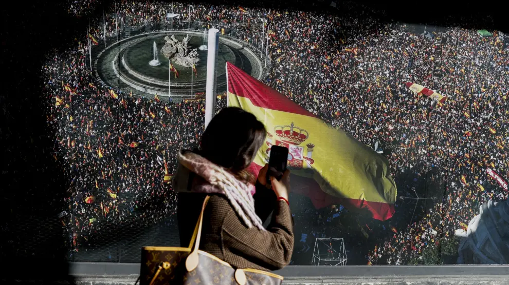 MADRID, 22/11/2023.- Una viandante toma una foto de una imagen de una manifestación contra la Ley de Amnistía celebrada en Madrid y que decora la fachada de la sede del Partido Popular en Madrid, este miércoles. EFE/ Mariscal